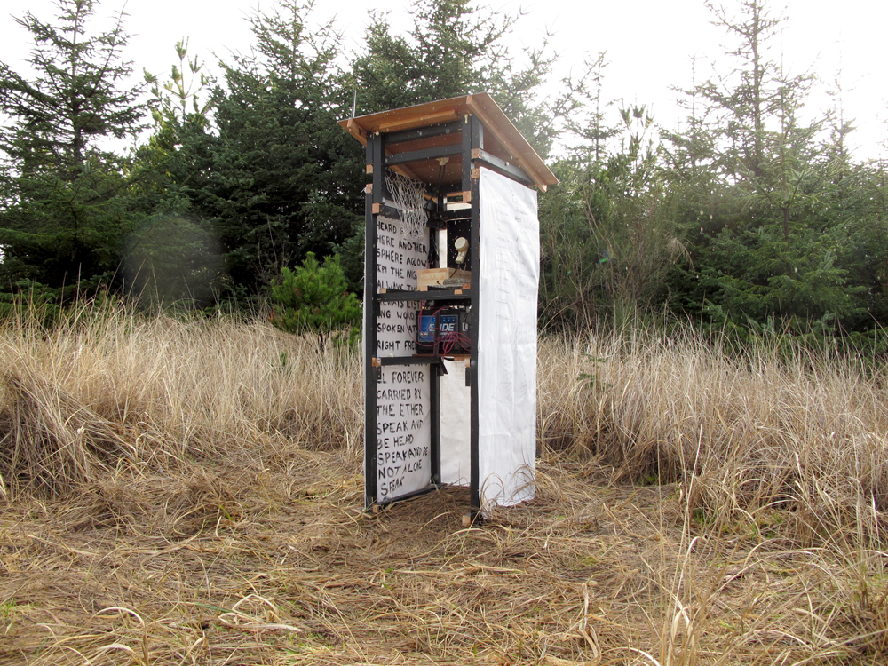 A small booth built of wood, standing on a hill, wrapped in canvas and containing a radio trasmitter