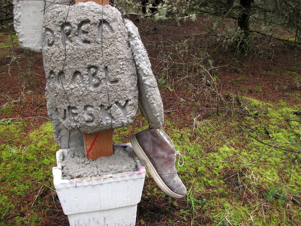 Concrete slab with text hanging from post and a shoe