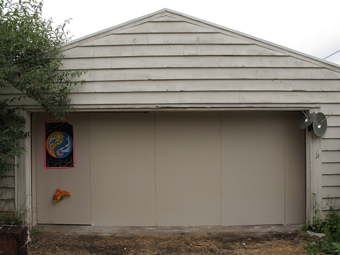 A residential garage, enclosed with a wall. A poster at the far left end.