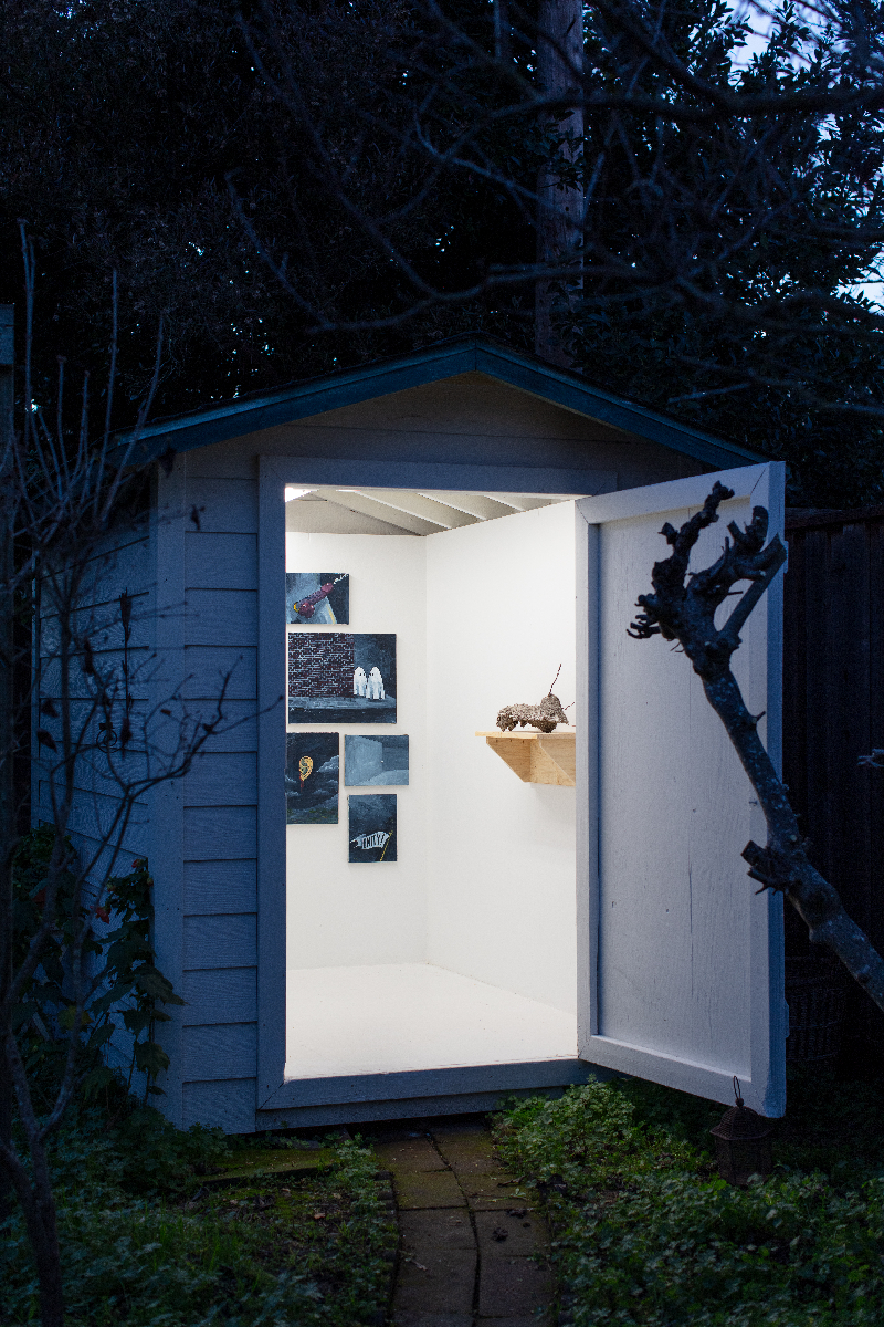 Sculptures and paintings inside a garden shed at night.